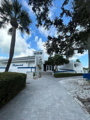 A building with a sign reading "Shipwatch" and a paved walkway leading to the entrance.