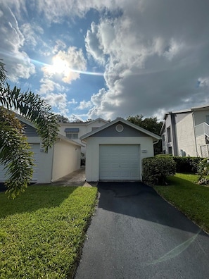 A residential driveway leading to a garage with a well-maintained lawn and a clear sky.