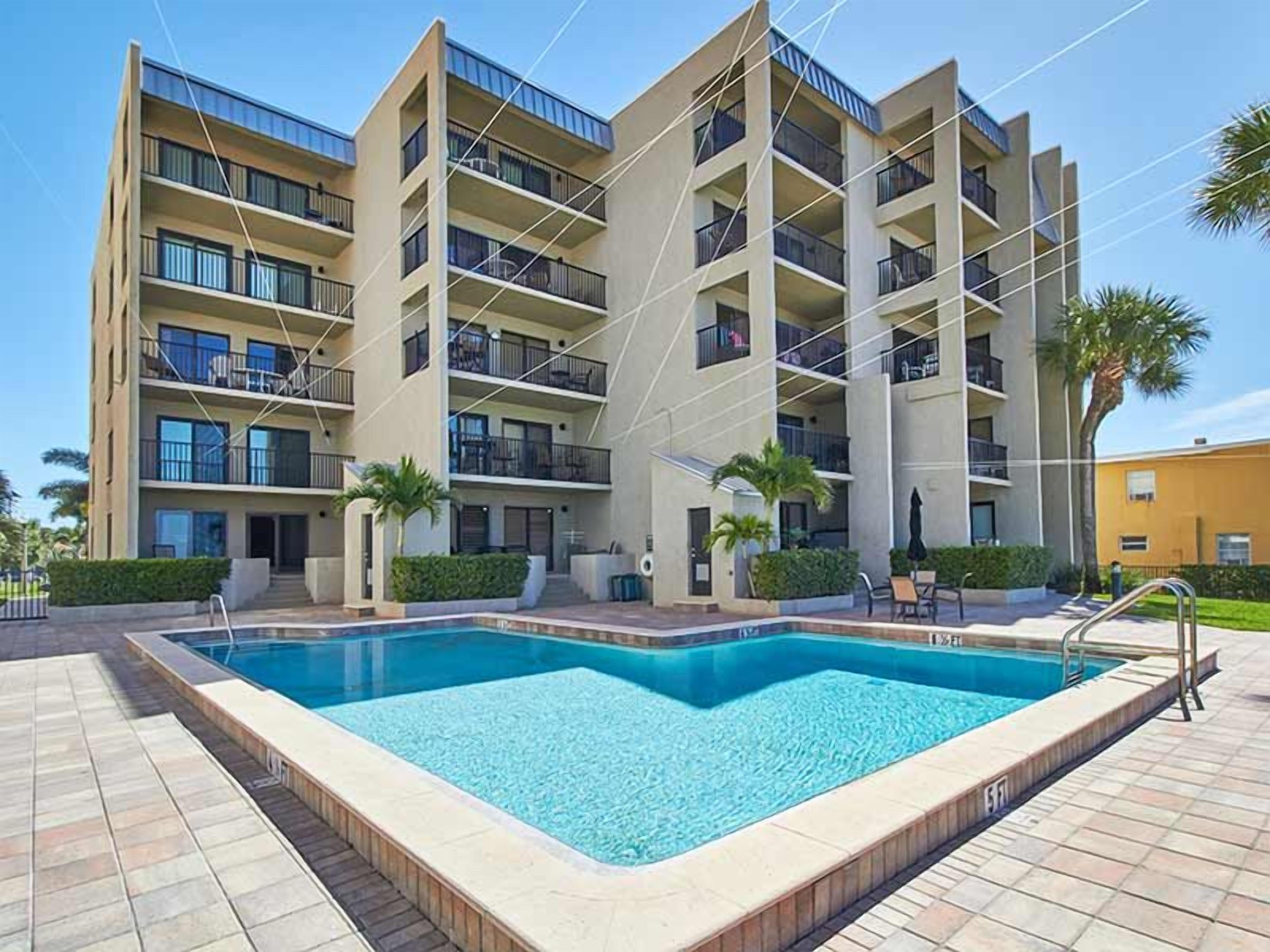 A multi-story building with a swimming pool in front.