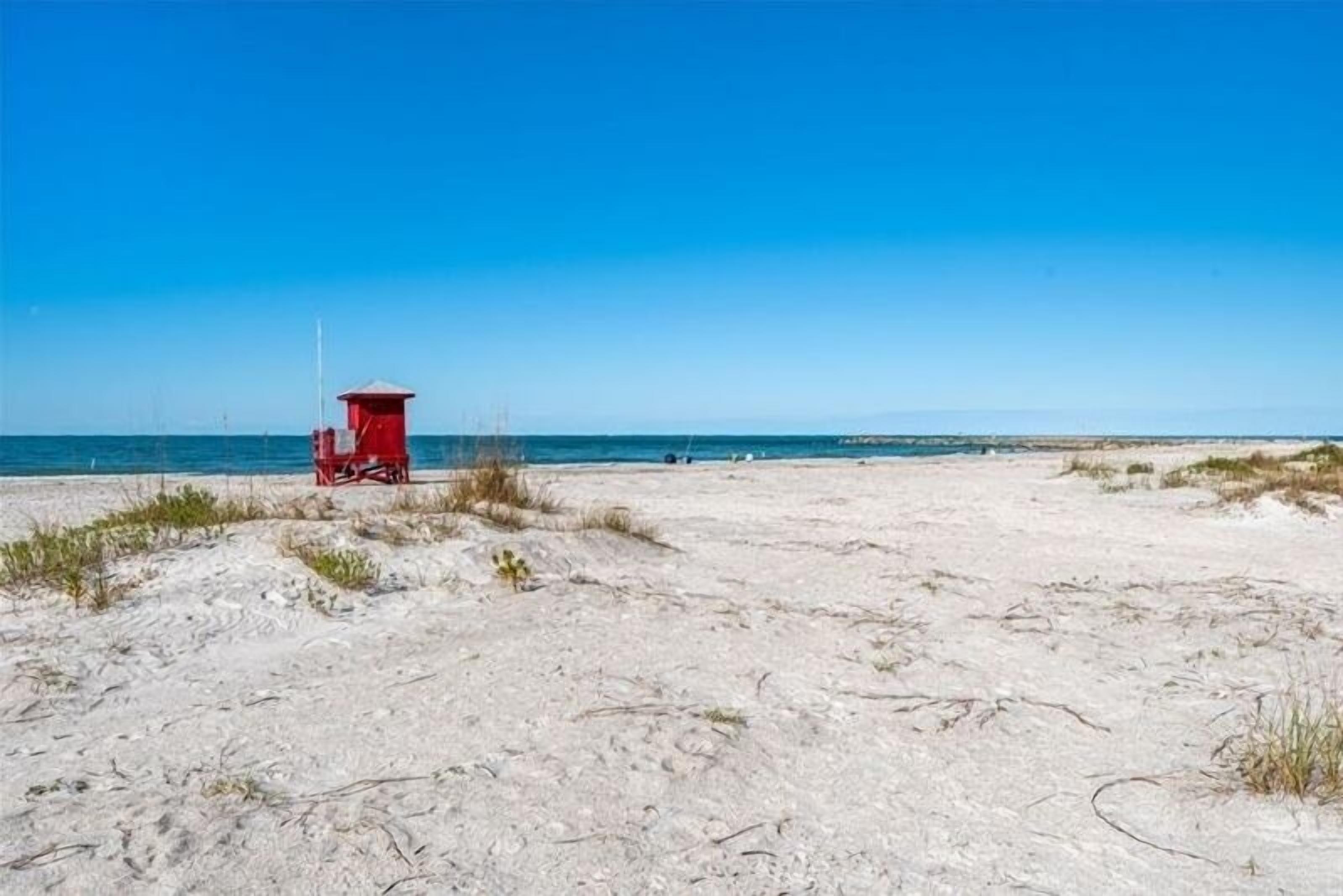 A sandy beach with a red lifeguard tower.