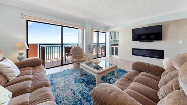 A spacious living room with a large window, a flat-screen TV, and a comfortable seating area.