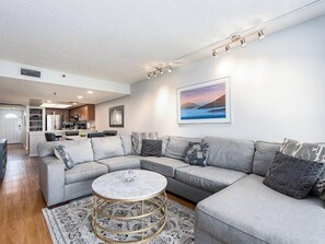 A modern living room with a sectional sofa, a round coffee table, and a kitchen in the background.