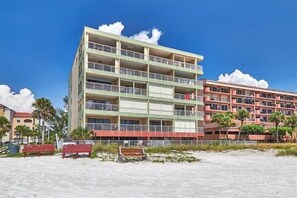 A multi-story hotel with balconies, located on a sandy beach with palm trees and other buildings in the background. - Pet Friendly, Direct Gulf Front Condo with Million Dollar Panoramic Views! ~ TP404 (Indian Shores)