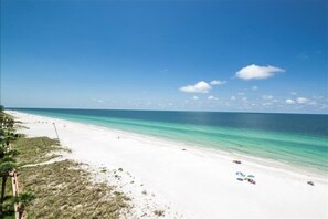 A beach with white sand, clear turquoise water, and a few umbrellas. - Pet Friendly, Direct Gulf Front Condo with Million Dollar Panoramic Views! ~ TP404 (Indian Shores)