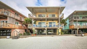 A multi-story hotel with balconies, a covered outdoor area, and a sandy ground.