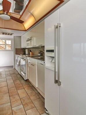Una cocina moderna con armarios blancos, horno empotrado, lavavajillas y refrigerador.