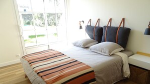 Un dormitorio con cama, mesita de noche, lámpara y ventana.