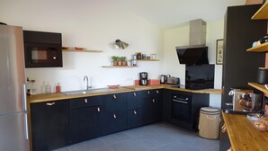 Una cocina moderna con armarios negros, un lavamanos de acero inoxidable, un microondas y una cafetera.