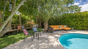 A backyard with a swimming pool, a wooden deck, and a seating area with a sofa and chairs. - Tropical oasis (Lake Worth)