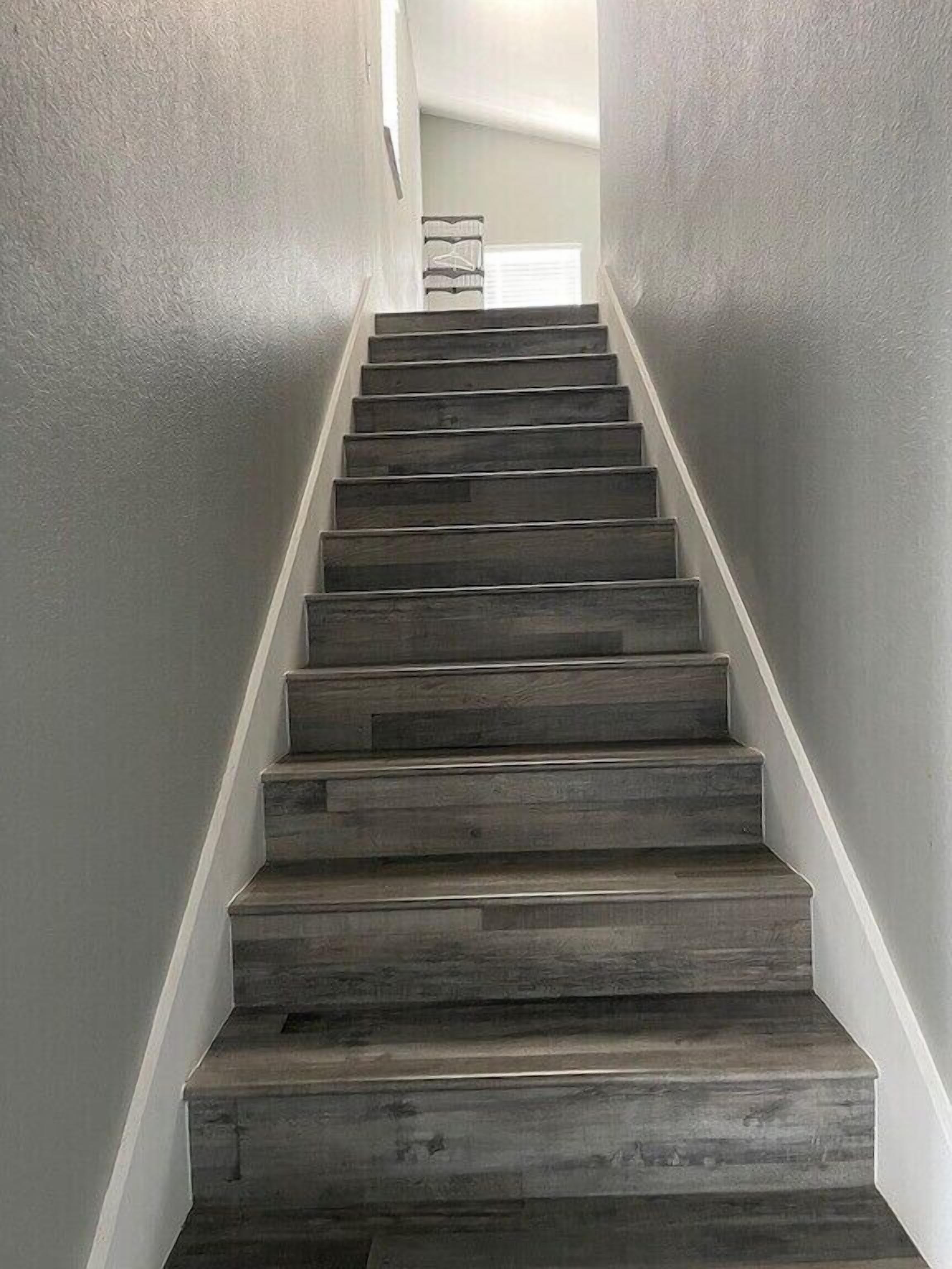 Eine Treppe mit dunklen Holzhäuschen und weißen Wänden.