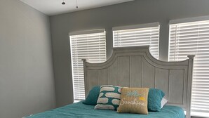 Ein Schlafzimmer mit einem Bett, einem Nachttisch und einem Fenster mit Jalousien.
