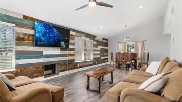 Ein modernes Wohnzimmer mit Flachbildfernseher, Holzwandgestaltung und Deckenventilator.