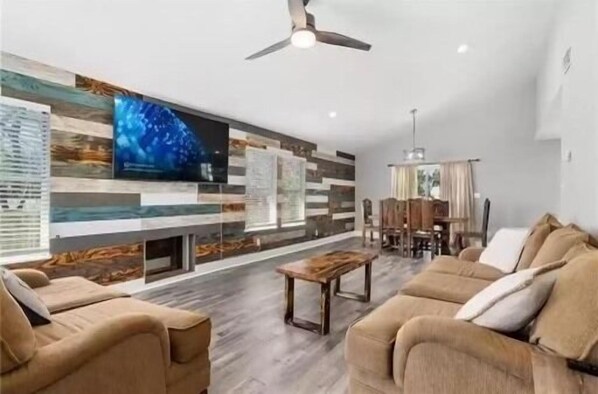 Relax in this stylish living room with a large flat-screen TV, dining area, and comfortable seating.