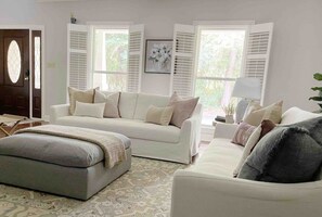 A living room with a sofa, ottoman, and a lamp.