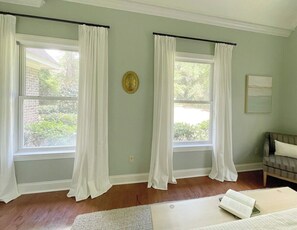 A room with two windows, a sofa, and a wall-mounted clock.