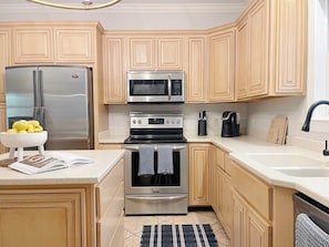 A kitchen with a stainless steel refrigerator, a microwave, an oven, and a sink.