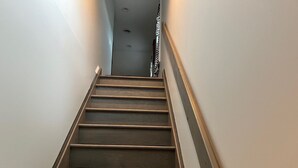 A wooden staircase with a handrail, leading upwards.