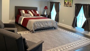 A bedroom with a large bed, a sofa, a rug, and a picture on the wall.