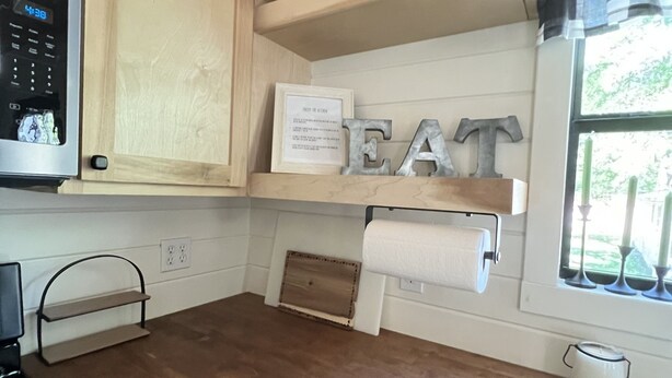 A kitchen with wooden cabinets, a microwave, a coffee maker, and a window with curtains. - Reel Life Lakehouse - Boat Ramp in Neighborhood (Broaddus)