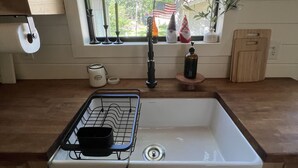 A kitchen with a window, a sink, a drying rack, and a cutting board. - Reel Life Lakehouse - Boat Ramp in Neighborhood (Broaddus)