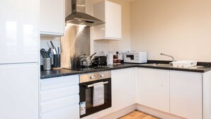 Una cocina moderna con gabinetes blancos, una campana extractora de acero inoxidable, un microondas, un tostador y un lavabo.