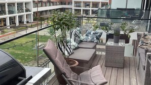 Ein Balkon mit Grill, einer Sitzecke und Topfpflanzen.