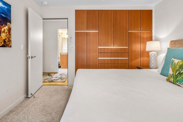Una habitación de hotel con una cama, una mesita de noche, una lámpara, un cuadro y un armario.