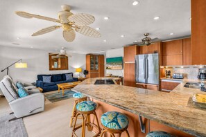 A modern kitchen with a central island, stainless steel appliances, and a dining area with a sofa and chairs.