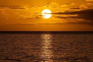 Un atardecer sobre una superficie de agua tranquila, con horizonte visible.