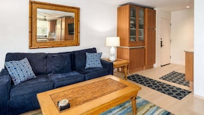 A living room with a dark blue sofa, a wooden coffee table, and a large mirror on the wall.