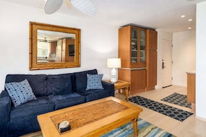 A living room with a dark blue sofa, a wooden coffee table, and a large mirror on the wall.