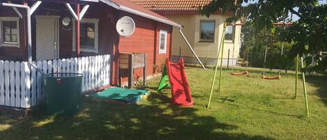 A house with a red roof, a white picket fence, a satellite dish, and a slide in the yard.