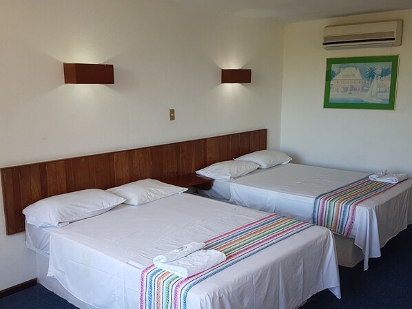 Two single beds with wooden headboards, white bedding, and a colorful striped blanket. There are wall-mounted lights and a framed picture on the wall. - Hotel El Doral (Tecolutla)