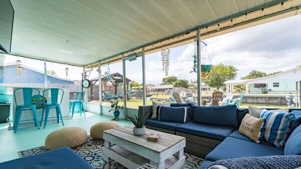 A covered outdoor seating area with a sofa, chairs, and a coffee table.
