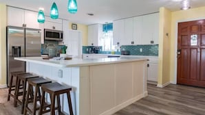 A modern kitchen with a large island, bar stools, and pendant lights.