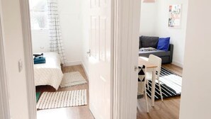 Una habitación con una cama, un sofá gris, un tapete a rayas negras y blancas y una lámpara colgante.