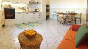 A compact kitchen with white cabinets, a built-in oven, and a dining area with wooden chairs and a table.