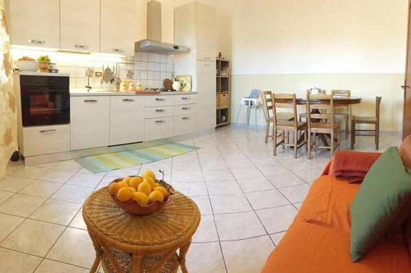 A compact kitchen with white cabinets, a built-in oven, and a dining area with wooden chairs and a table.
