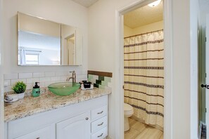 Ein Badezimmer mit einem weißen Waschbecken, einem grünen Seifenspender und einer Glas-Schale.