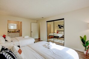 Ein Hotelzimmer mit zwei Betten, einem Badezimmer und einer Schiebetür zu einem weiteren Raum.