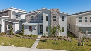 A modern multi-story residential building with a stone facade, multiple windows, and a well-maintained lawn.