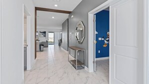 A hallway with a marble floor, a console table, and a mirror on the wall.