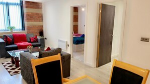 A living room with a sofa, armchairs, and a coffee table. There is a brick wall and a window with blinds. - Charming 1-bed Apartment in Bradford City Holiday (Bradford)