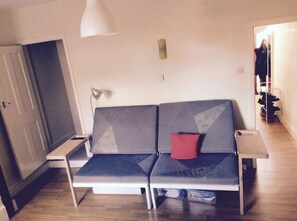 A modern living room with a grey sofa, a red pillow, a white floor lamp, and a small table. - MASTER BEDROOM IN ❤️ OF LEICESTER (Leicester)