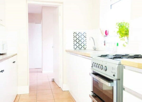 A kitchen with white cabinets, a stove, and a tiled backsplash.