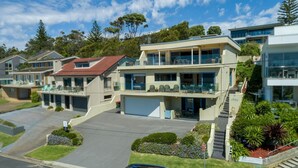 A modern two-story house with a garage, a balcony, and a well-maintained garden.