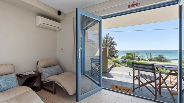 A room with a sliding glass door leading to a balcony with a view of the sea.