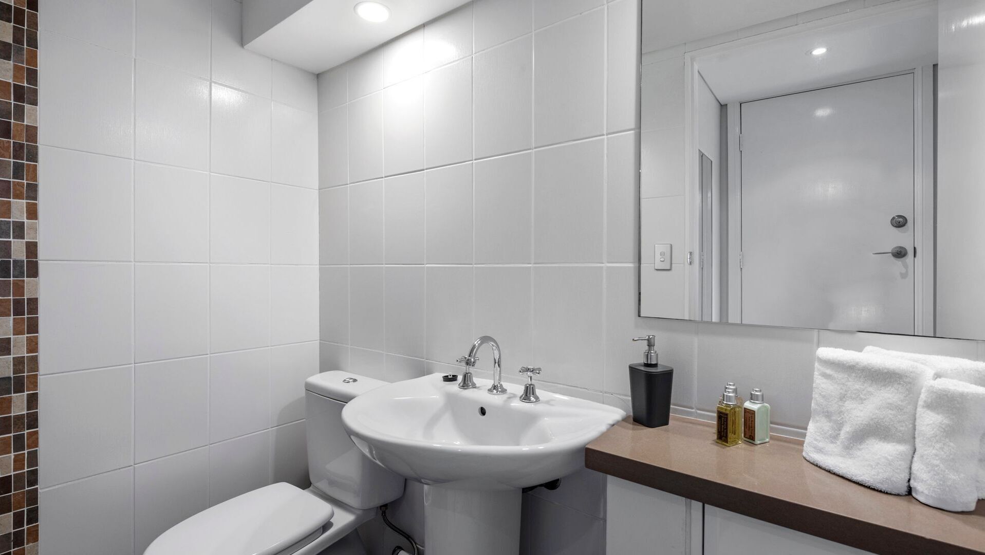 Uma casa de banho moderna com uma sanita, lavatório e toucador brancos.