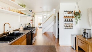 A modern kitchen with wooden cabinets, a stainless steel sink, and a coffee machine.