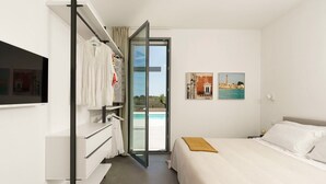 Et hotelværelse med seng, fjernsyn, garderobeskab og dør til en swimmingpool.